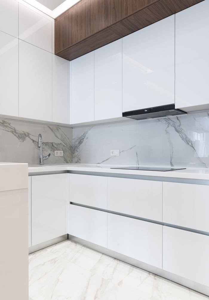 Sleek, white kitchen design highlighting modern cabinetry and elegant marble finishes.